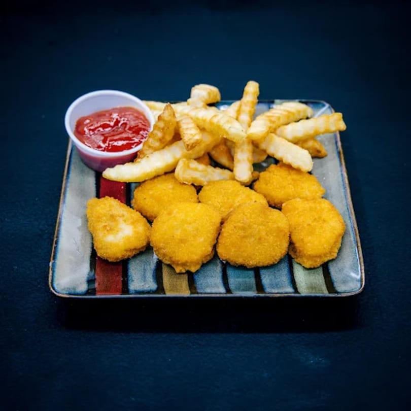 A plate of golden chicken nuggets, crinkle-cut fries, and a side of ketchup.